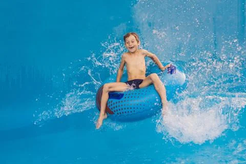 Boy on a pool float on artificial waves in a water park Stock Photos