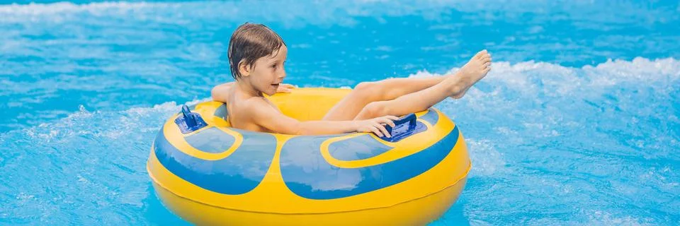 Boy on a pool float on artificial waves in a water park BANNER, LONG FORMAT Stock Photos