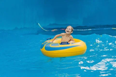 Boy on a pool float on artificial waves in a water park Stock Photos