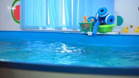 The boy in the pool with swimming goggles dives. He gets toys from the bottom Stock-Footage 101497772