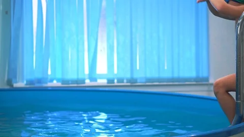 The boy in the pool with swimming goggles jumping into the water. Vidéo 101497789