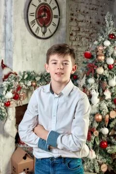 A boy poses on camera against the background of a New Year tree and decorations Foto stock