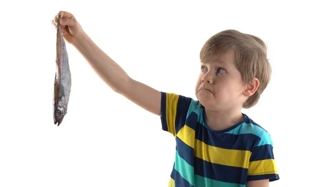 Boy posing in studio on a white background with raw fish, grimaces of disgust Stock Footage 124459434