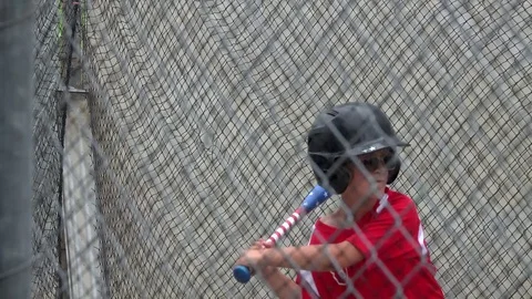 A boy practices baseball at a batting cage with a red white and blue American fl Stock Footage 70465108