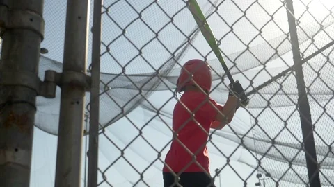 A boy practices little league baseball at the batting cages and bunting the ball Stock Footage