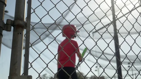 A boy practices little league baseball at the batting cages and walks out leavin Stock Footage
