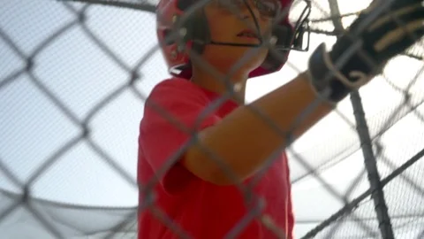A boy practices little league baseball at the batting cages and walks out leavin Stock Footage