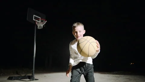 Boy practicing basketball skills in slow motion under outdoor lights Stock-Footage 293245993