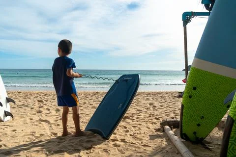 A boy practicing how to surf on the beach. Stock Photos