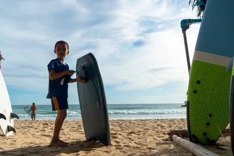 A boy practicing how to surf on the beach. Stock Photos