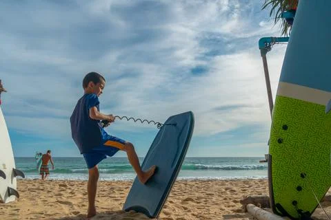 A boy practicing how to surf on the beach. Stock Photos