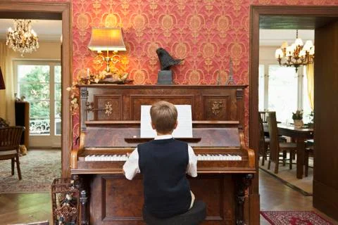 A boy practicing on an old-fashioned upright piano Stock Photos