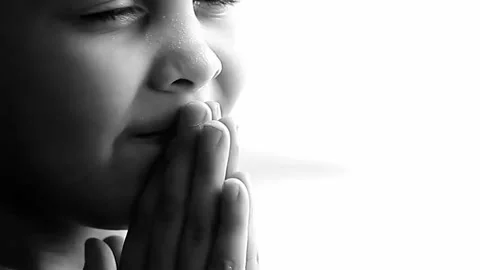 Boy praying to God with hands held together with people sock footage stock video Stockbeeldmateriaal 333011500