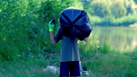 A boy prepares a bag to collect plastic waste Stock Footage 340464260
