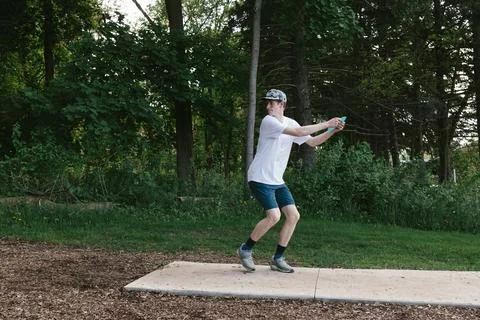 Boy prepares to throw disc while playing disc golf in woods Stock Photos