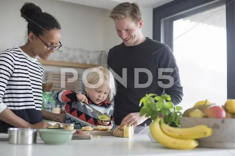 Boy Preparing Food In Kitchen With Parents