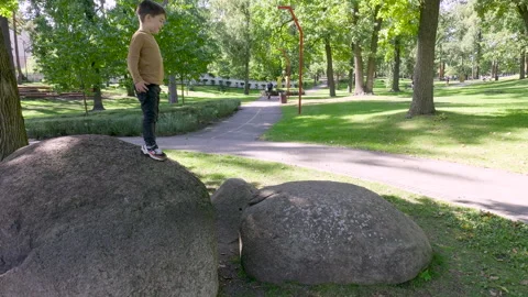The boy is preparing to jump from stone to stone. Excitement before the jump. Stock Footage 251831389