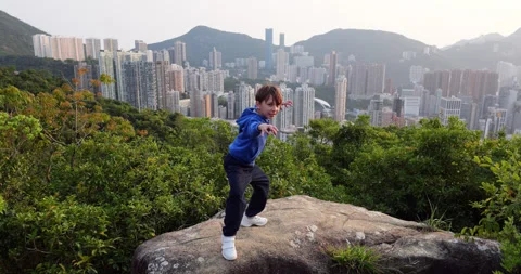 Boy pretend he practicing kung fu on mountain top above Hong Kong Stock-Footage 322098874