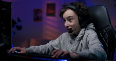 Boy pro gamer spends time playing computer games, focused experiencing the Stock Footage 176968641