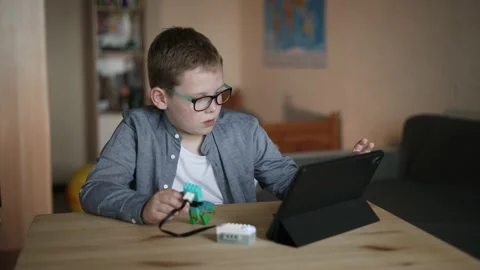 Boy program algorithm of toy on tablet. Child is embarrassed, failed attempt. Video stock 198179571