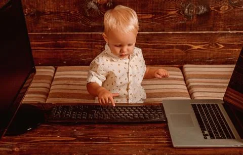 Boy programming on computer with multiple monitors and laptop on desk 스톡 사진