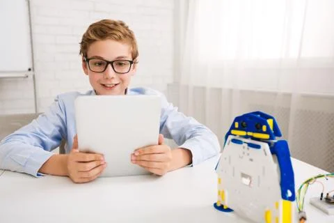 Boy programming robot with digital tablet in class 스톡 사진