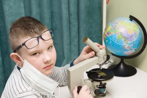 Boy in a protective mask studies a microscope Foto stock