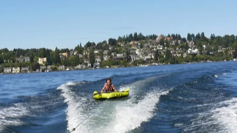 Boy pulled on inner tube behind motorboat, Lake Washington, Seattle. Stock Footage 98011443