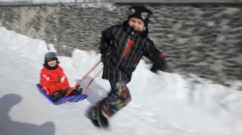 Boy pulling his little brother in a sledge Stock Footage 37134070