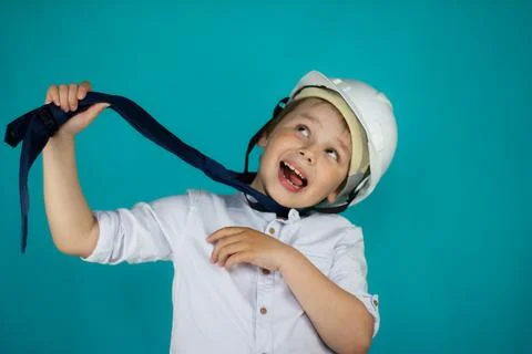 The boy is pulling his tie in a construction helmet and sticking out his tongue Stock Photos