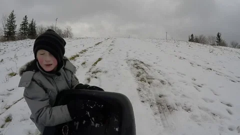 Boy pulling sled up hill in snow - slow motion Stock Footage 70007128