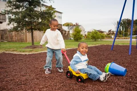 Boy Pulling Younger Brother in Wagon at Playground, Maryland, USA Stock Photos