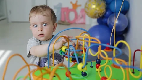 The boy pulls the ball on the string and plays with the toy standing in the room Stock Footage 154371156