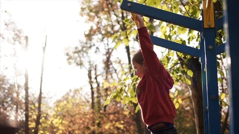 Boy pulls himself up on a horizontal bar. Slow Motion Stock Footage 88379607