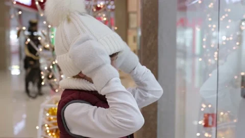 Boy pulls his white hat over his eyes near the window in market. Stock Footage 164414536
