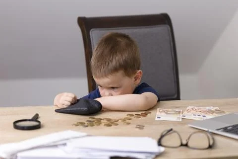 The boy pulls out money from a black wallet and counts coins. Stock Photos
