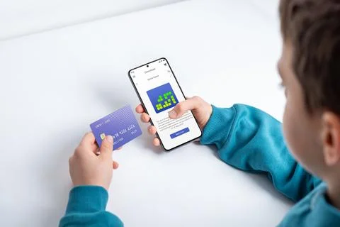 Boy purchasing a mobile game on a smartphone, illustrating the concept Stock Photos