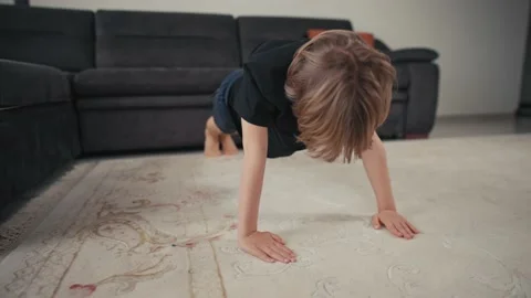 The boy is pushing up from the floor at home. Quarantine and sport concept. The Stock Footage 171972747