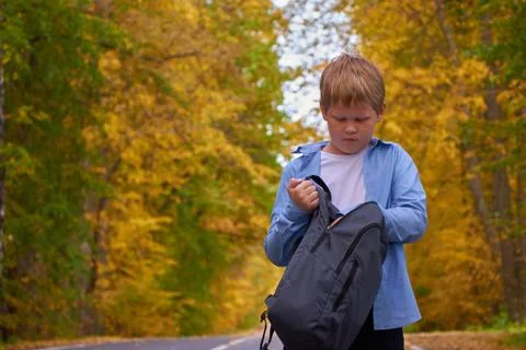 The boy put his hand in the school bag on the street Stock Photos