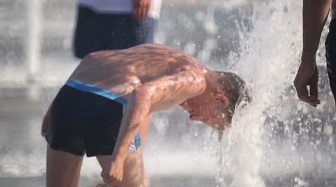The boy put his head under the jet of the fountain Stock Footage 59998443