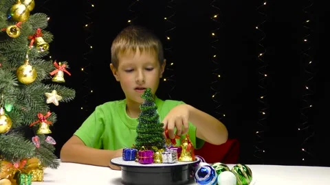 A boy puts Christmas decorations on a rotating surface Stock Footage 253311376