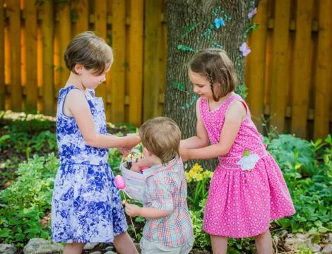 Boy Puts Egg in Girl's Easter Basket Stock Photos