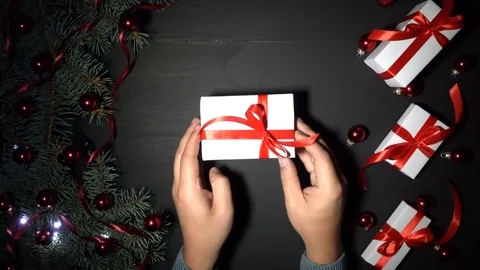 A boy puts a gift on the table, xmas background with fir branches and lights 스톡 동영상 99063351