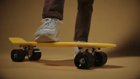 Boy puts one foot on a yellow penny board, close shot Stock Footage 168224466