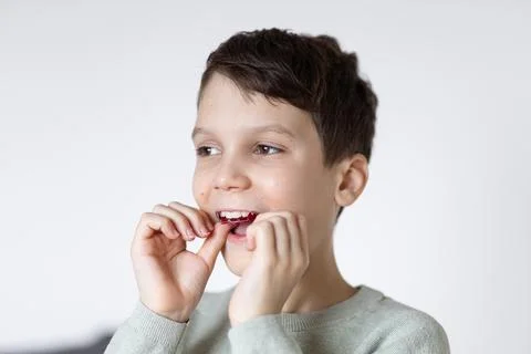 A boy puts on retainers, on a white background. Concept of correcting crooked Stock Photos