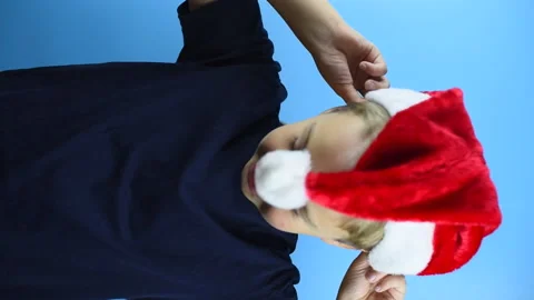Boy puts on a Santa hat, vertical video Stock Footage 141790485