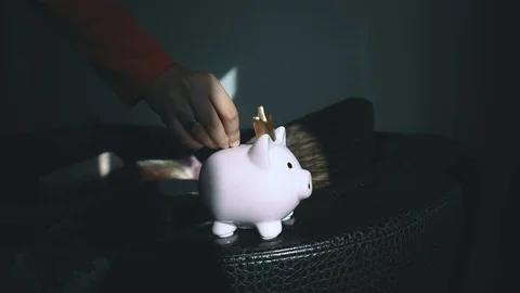 Boy putting a coin inside his piggy bank.  Investishions. Stock Footage 100972748