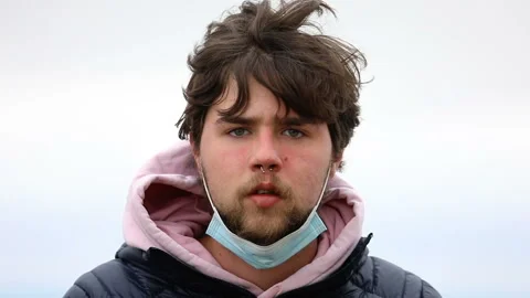 A boy putting on a face mask on a windy day Stockbeeldmateriaal 141062274