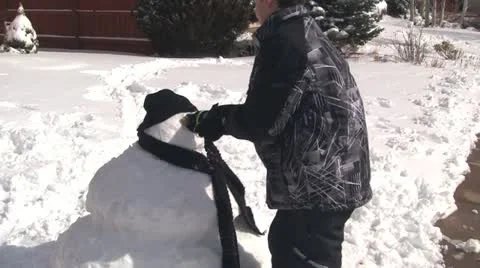 Boy putting face on snowman Stock Footage 21443712