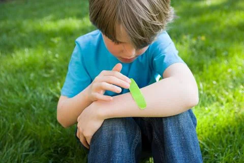 Boy putting plaster on arm Stock Photos